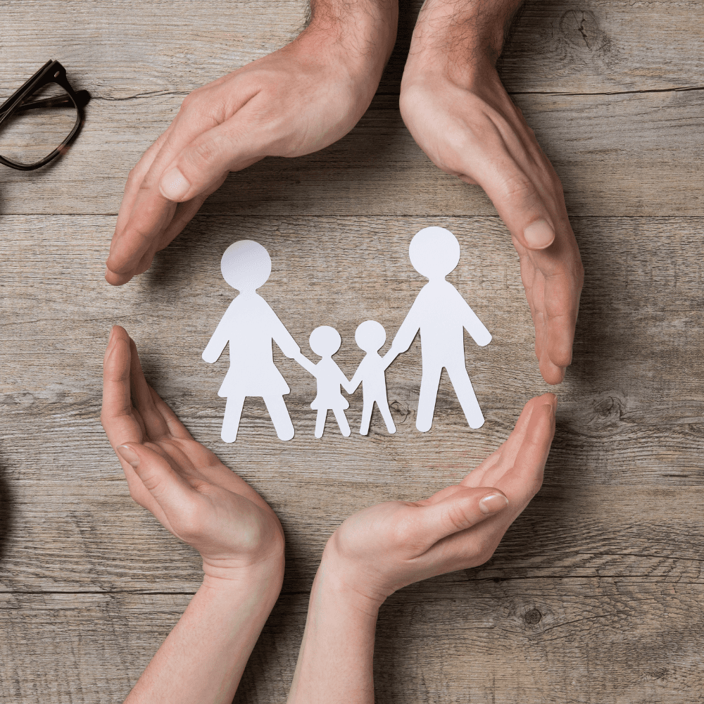 Cupped hands protecting a paper cut-out of a family