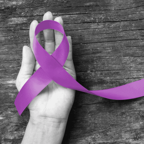 A hand holding a purple Alzheimer's awareness ribbon